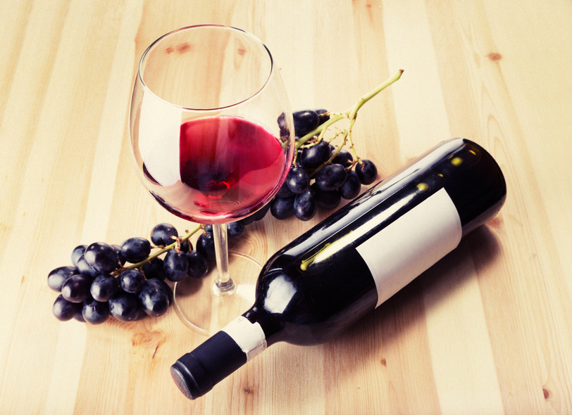 Red wine glass bottle and grapes on wood table