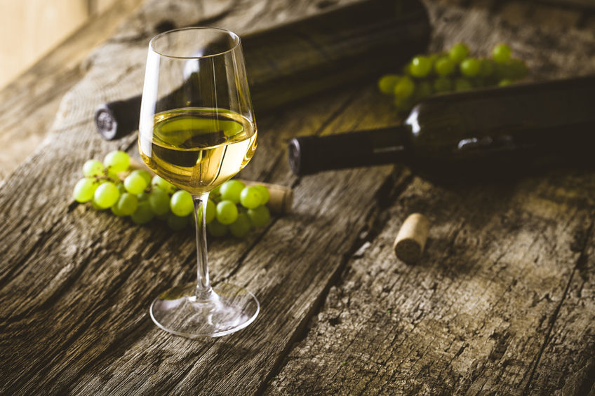 A glass of white wine next to green grapes