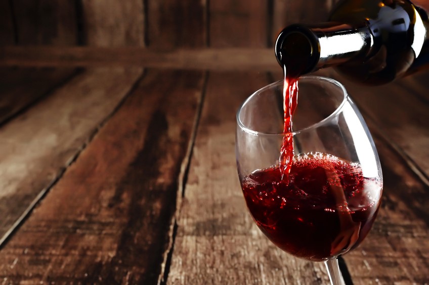 a bottle of red being poured into a glass after being stored in a spiral cellar